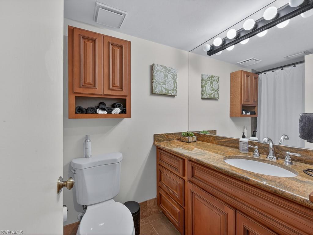910 Vanderbilt Beach Road, Unit 317W Naples, FL 34108 - Photo 9 of 14 a bathroom with a granite countertop toilet sink and mirror