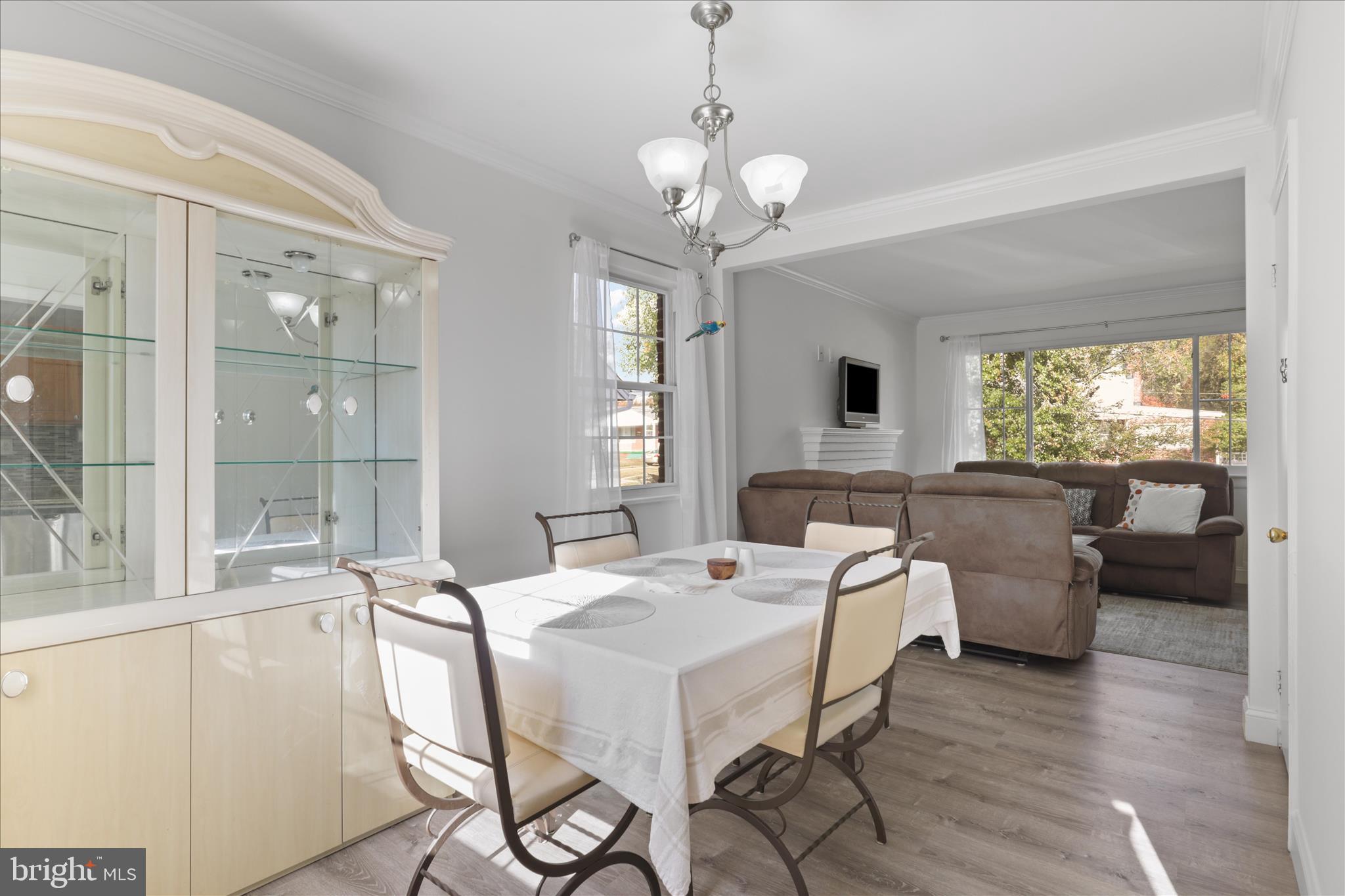 10602 Edgewood Avenue Silver Spring, MD 20901 - Photo 41 of 66 a dining room with wooden floor a chandelier a glass table and chairs