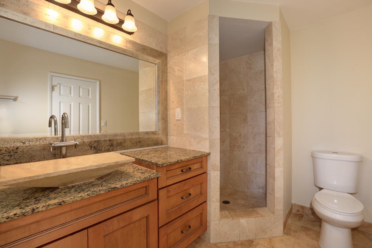 5045 Lower Honoapiilani Road, Unit 6 Lahaina, HI 96761 - Photo 25 of 30 a bathroom with a granite countertop sink a toilet and a mirror