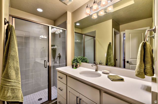 1622 Canyon Tree Drive St. George, UT 84770 - Photo 17 of 34 Spacious bathroom featuring a glass-enclosed shower with subway tile surround, a large vanity with an integrated sink, and a wall-mounted mirror with overhead lighting