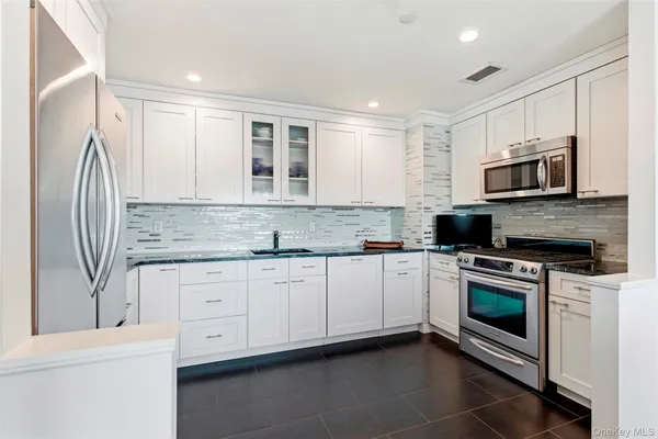 a kitchen with stainless steel appliances granite countertop a stove a sink and a microwave