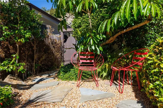 a backyard with table and chairs potted plants and large tree