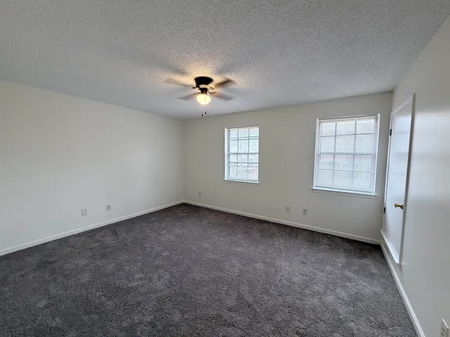 an empty room with windows and chandelier fan