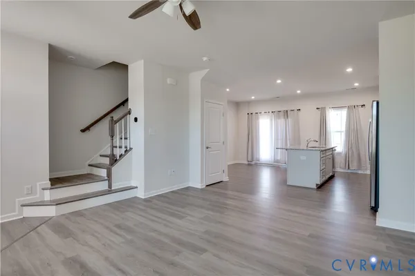 a view of an empty room with wooden floor and staircase