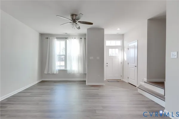 a view of empty room with wooden floor and fan