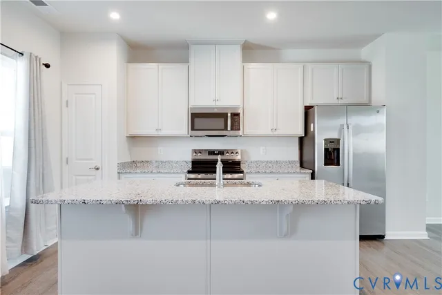 a kitchen with kitchen island a counter top space cabinets and stainless steel appliances