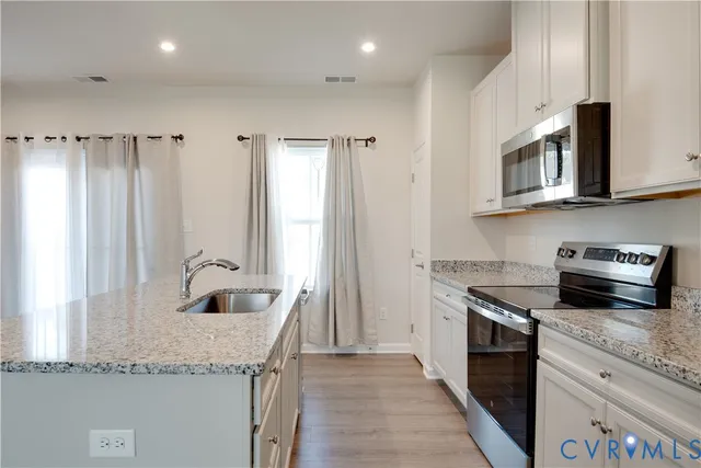 a kitchen with granite countertop stainless steel appliances a sink stove and cabinets