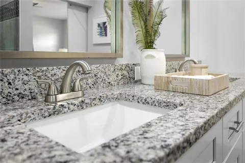 a bathroom with a granite countertop sink a mirror and a bathtub