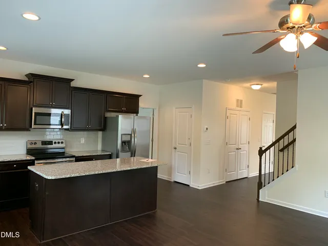 a kitchen with stainless steel appliances granite countertop a refrigerator a sink a stove a microwave and a counter space