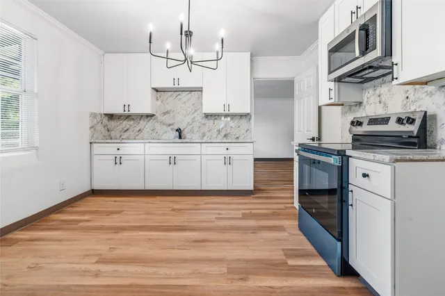 a kitchen with stainless steel appliances granite countertop a sink a stove a refrigerator and island with wooden floor