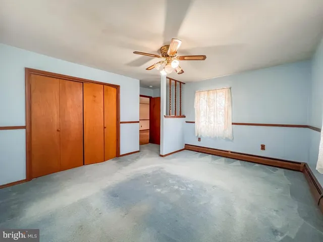 an empty room with chandelier fan and windows