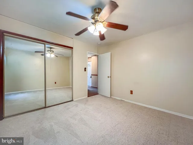 an empty room with closet and a chandelier fan