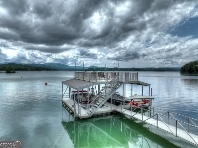 a kitchen with stainless steel appliances kitchen island granite countertop a refrigerator a stove a sink dishwasher and white cabinets with wooden floor