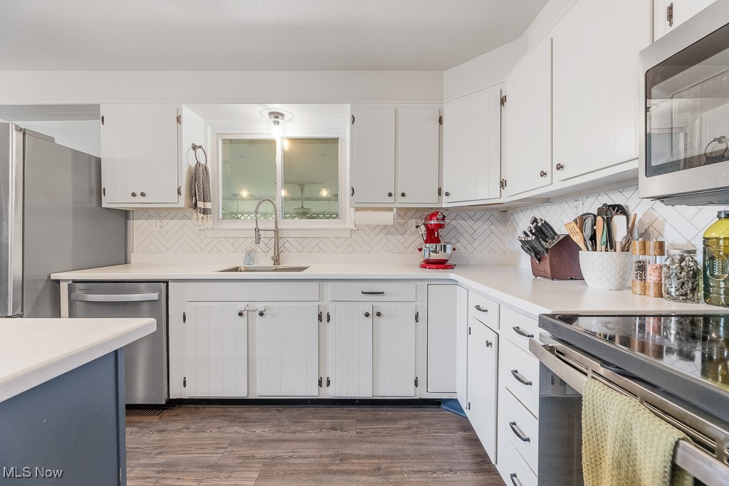 3166 Work Road Ravenna, OH 44266 - Photo 11 of 48 Kitchen featuring tasteful backsplash, sink, white cabinets, appliances with stainless steel finishes, and dark hardwood / wood-style flooring