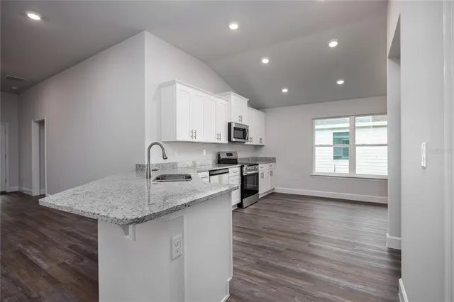 a kitchen with granite countertop wooden floors a sink and appliances
