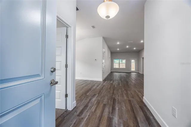 an empty room with wooden floor and entrance