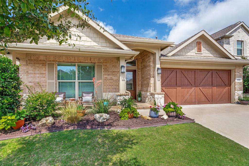 5556 Vaquero Road Fort Worth, TX 76126 - Photo 2 of 25 Brick and stone facade featuring a wood-panel garage door, covered entry. Gorgeous front flower bed and wonderful curb appeal.
