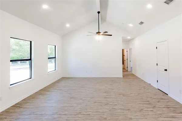 a view of empty room with wooden floor and ceiling fan