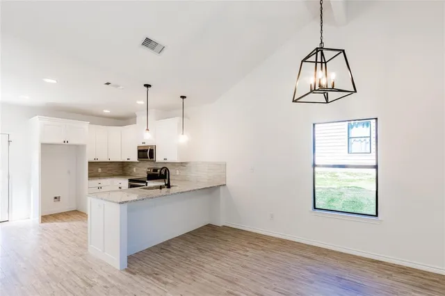 a kitchen with stainless steel appliances granite countertop a sink a microwave a stove and a wooden floors