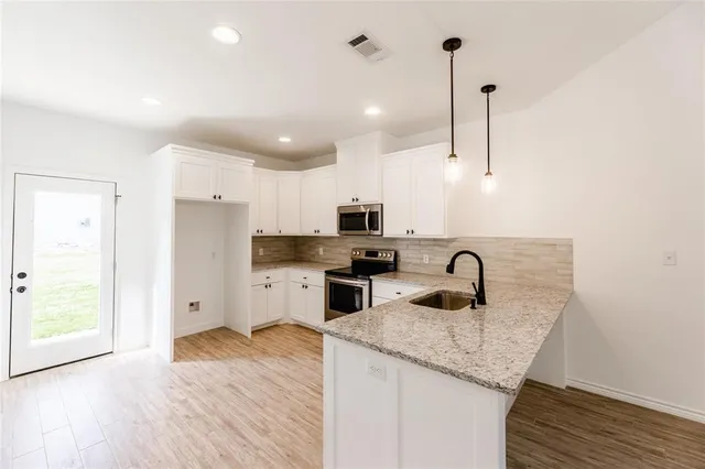 a kitchen with a refrigerator sink and cabinets
