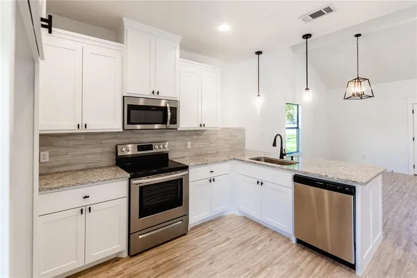 a kitchen with granite countertop stainless steel appliances and wooden floor