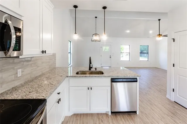 a kitchen with granite countertop a sink a counter space appliances and cabinets