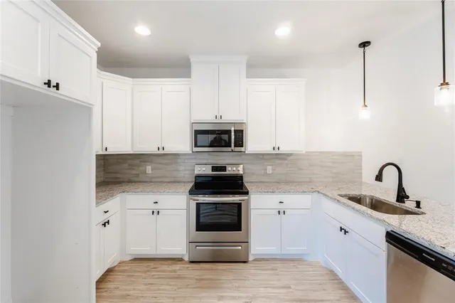 a kitchen with granite countertop white cabinets and stainless steel appliances