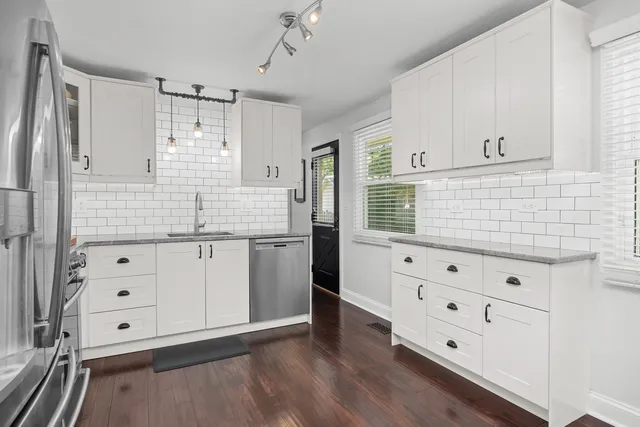 a kitchen with white cabinets and window