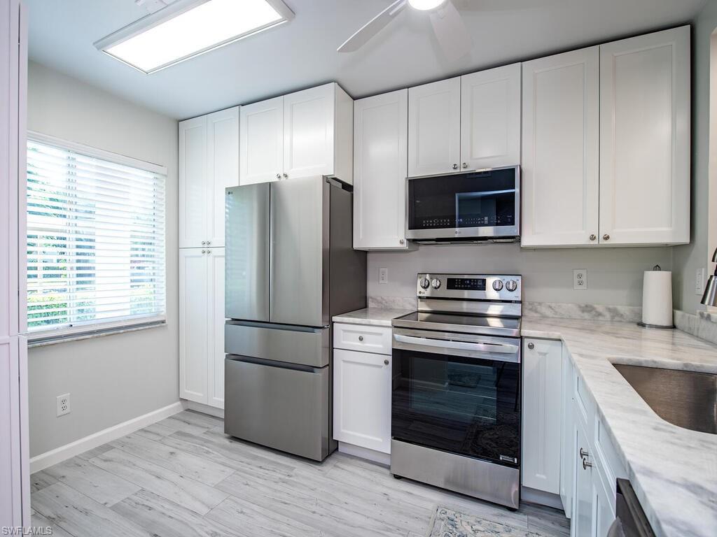 4556 Andover Way, Unit E104 Naples, FL 34112 - Photo 5 of 12 a kitchen with a stove microwave and a refrigerator