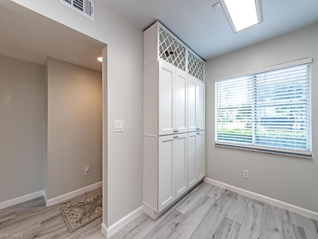 4556 Andover Way, Unit E104 Naples, FL 34112 - Photo 6 of 12 a view of an empty room with wooden floor and a window