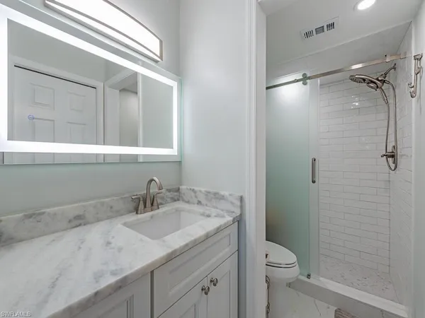 a bathroom with a granite countertop sink toilet and shower