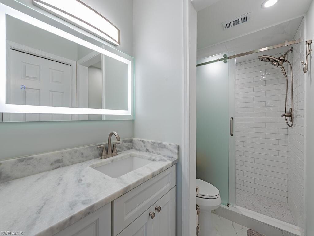 4556 Andover Way, Unit E104 Naples, FL 34112 - Photo 8 of 12 a bathroom with a granite countertop sink toilet and shower