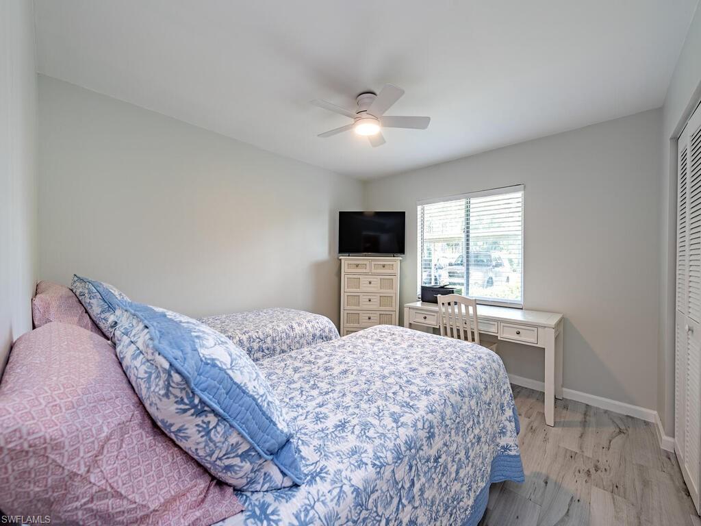 4556 Andover Way, Unit E104 Naples, FL 34112 - Photo 9 of 12 a bedroom with a large bed and a flat tv screen