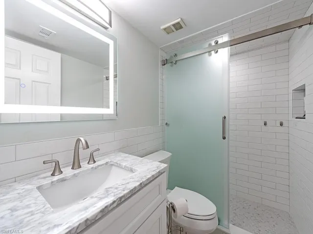 a bathroom with a granite countertop sink toilet a mirror and shower