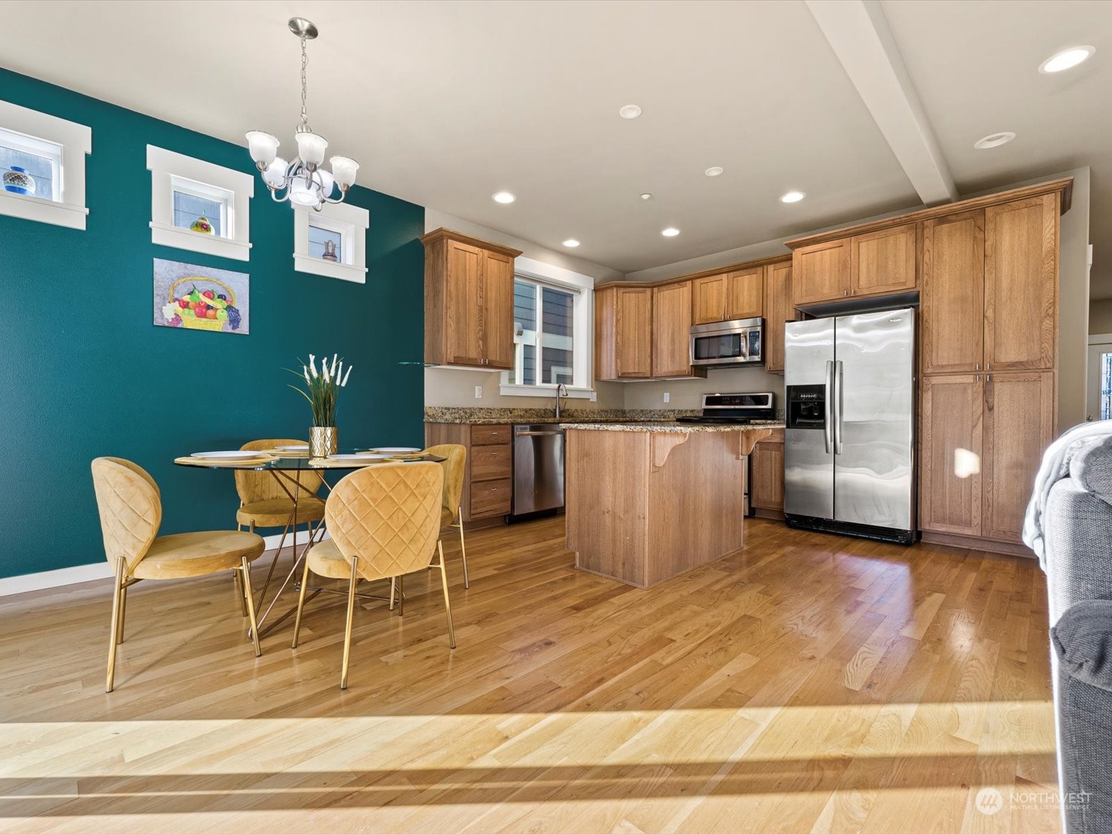 4831 Northeast 13th Place Renton, WA 98059 - Photo 6 of 24 a kitchen with stainless steel appliances kitchen island granite countertop a refrigerator a stove top oven and a dining table with wooden floor