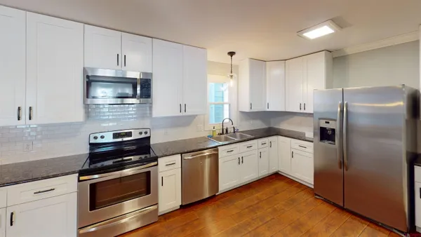 a kitchen with granite countertop white cabinets stainless steel appliances and a counter space