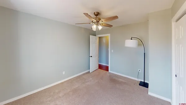 an empty room with a ceiling fan and carpet