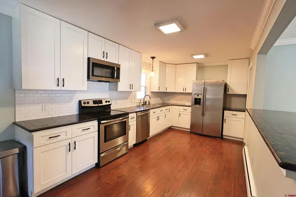 a kitchen with wooden floors and white appliances