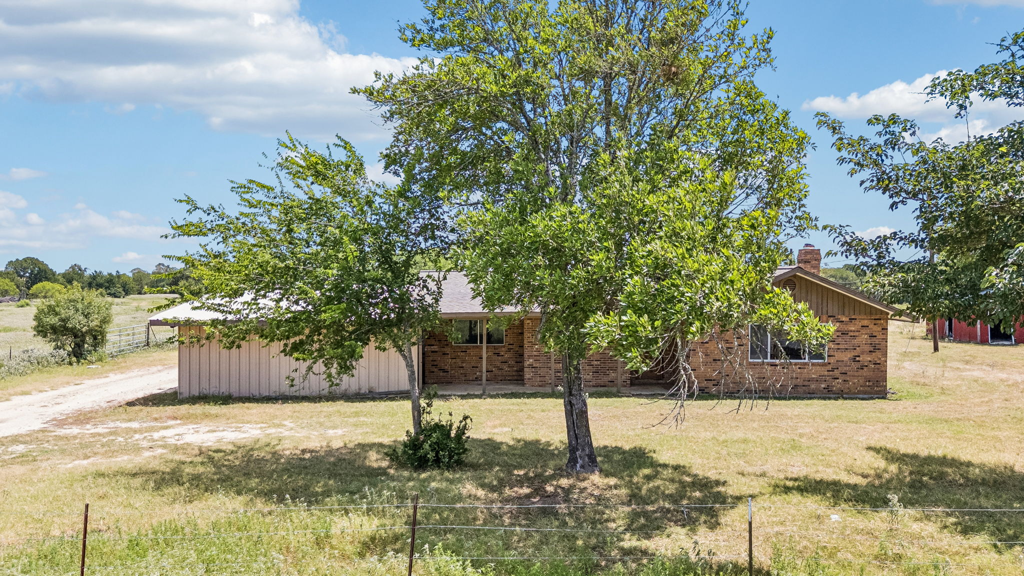 9765 A State Park Road Lockhart, TX 78644 - Photo 24 of 30 A classic brick residence nestled amidst a verdant landscape, featuring a traditional pitched roof and mature trees.