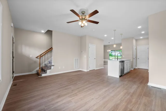 a view of an empty room with wooden floor and a ceiling fan