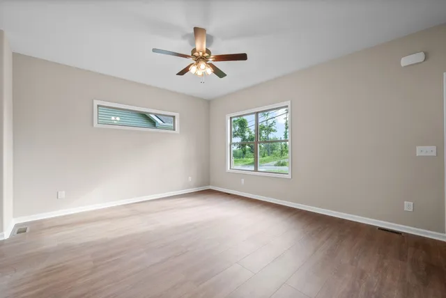 a view of room with window ceiling fan and hardwood floor