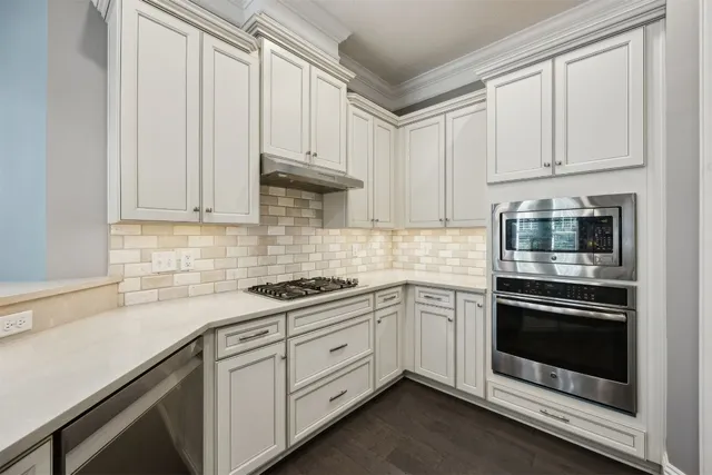 a kitchen with granite countertop white cabinets and stainless steel appliances