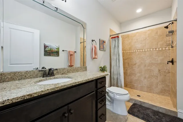 a bathroom with a granite countertop sink toilet a large mirror a shower and a mirror