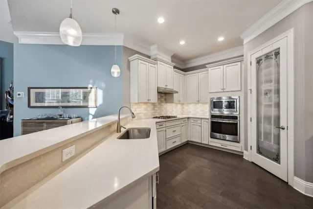 a large white kitchen with cabinets a sink and appliances