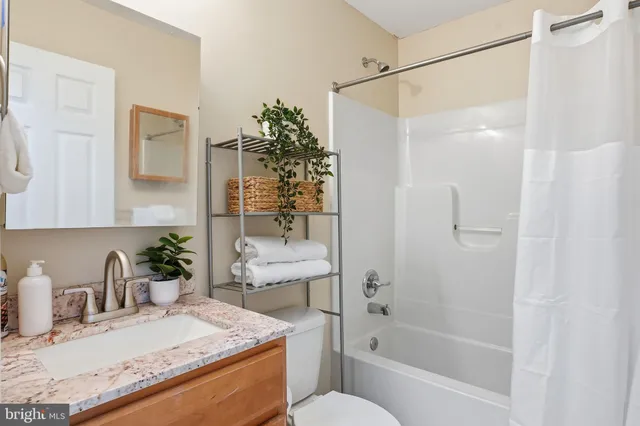 a bathroom with a granite countertop sink a toilet and shower
