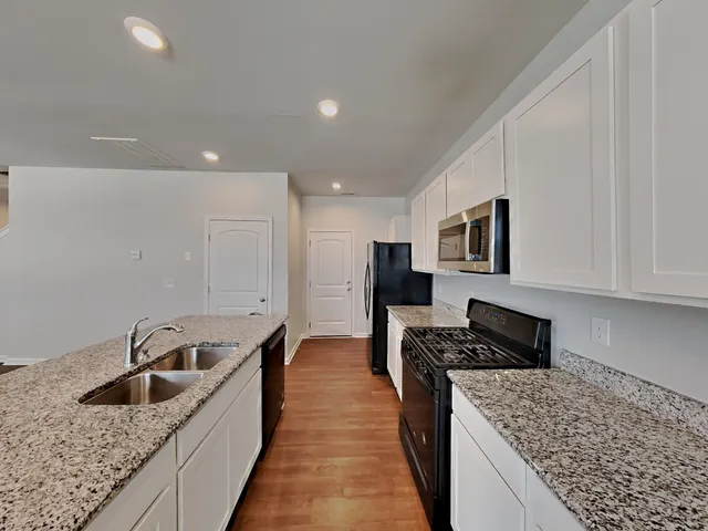 a kitchen with stainless steel appliances granite countertop a sink stove and refrigerator