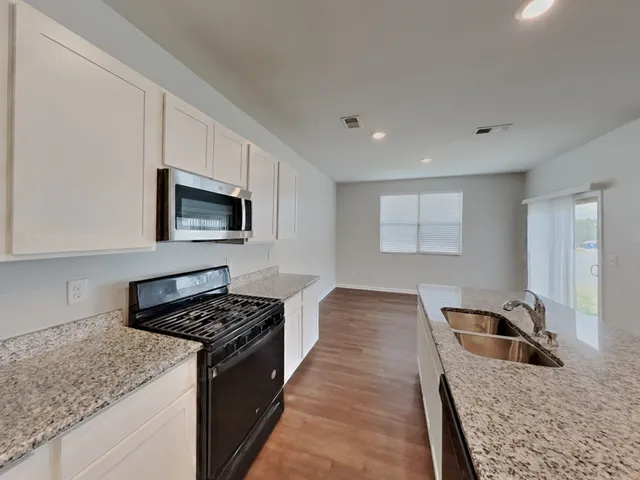 a kitchen with granite countertop stainless steel appliances sink stove and cabinets