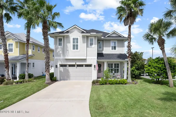 a front view of a house with a garden and palm trees