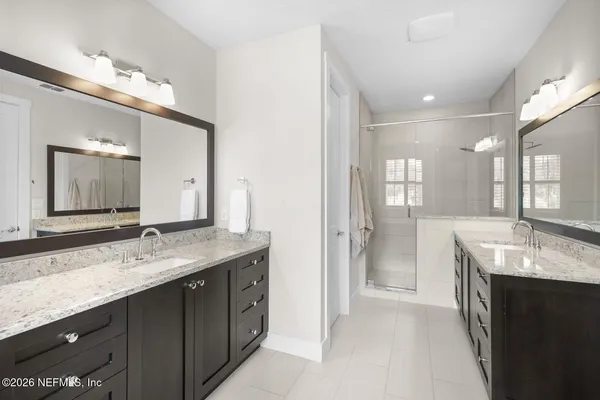 a bathroom with a granite countertop double vanity sink a large mirror a bathtub and window