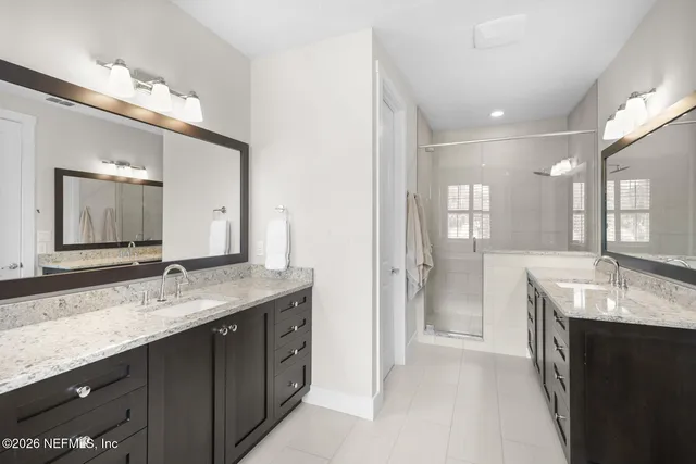 a bathroom with a granite countertop double vanity sink a large mirror a bathtub and window